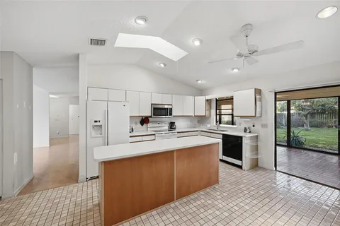 a large white kitchen with a stove a sink dishwasher and a refrigerator with wooden floor