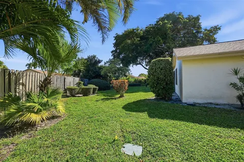 a view of a white house with a yard and table and chairs under an umbrella