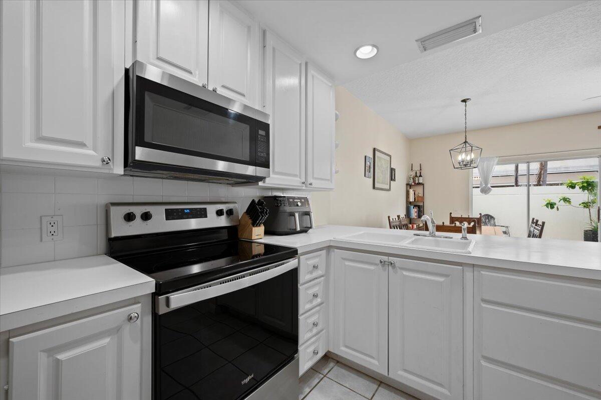 11 Live Oak Circle, Unit 11 Tequesta, FL 33469 - Photo 18 of 27 a kitchen with white cabinets and appliances