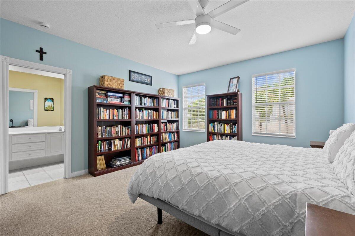 11 Live Oak Circle, Unit 11 Tequesta, FL 33469 - Photo 25 of 27 a bedroom with a large bed a chandelier and a book shelf