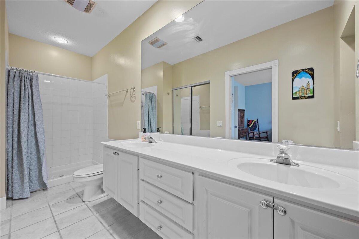 11 Live Oak Circle, Unit 11 Tequesta, FL 33469 - Photo 26 of 27 a bathroom with a double vanity sink toilet and a mirror