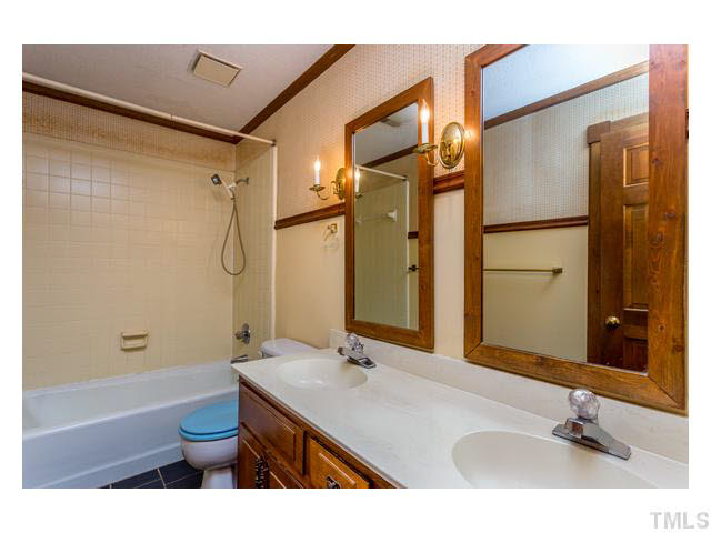 8205 Holly Berry Court Raleigh, NC 27615 - Photo 20 of 24 a bathroom with a sink a toilet a mirror and shower