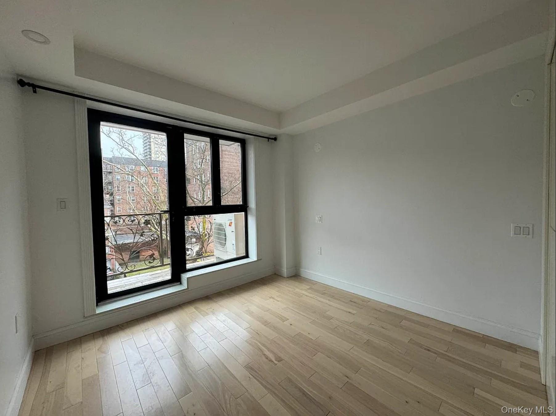 105-25 65th Road, Unit 5C Queens, NY 11375 - Photo 4 of 8 an empty room with wooden floor and large window