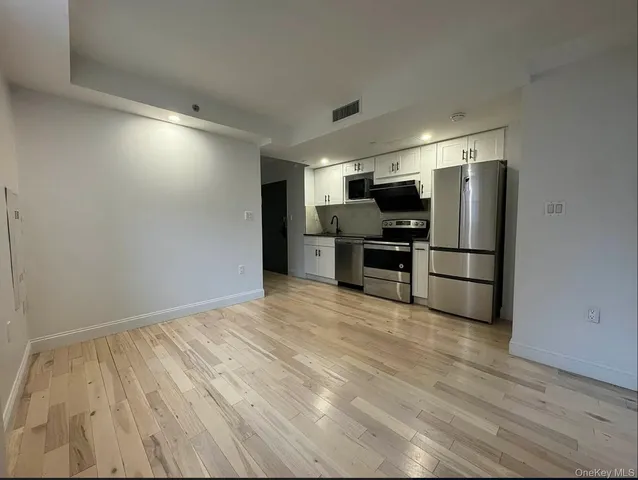 a view of kitchen with wooden floor electronic appliances and cabinets