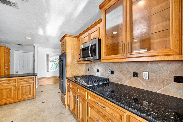 a kitchen with stainless steel appliances granite countertop a stove a sink and a microwave