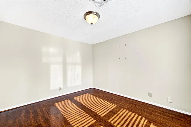 a view of an empty room with wooden floor and window