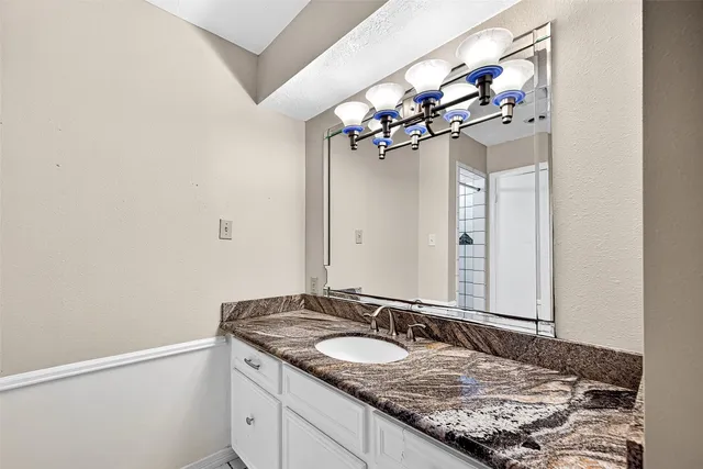 a bathroom with a granite countertop double vanity and a mirror