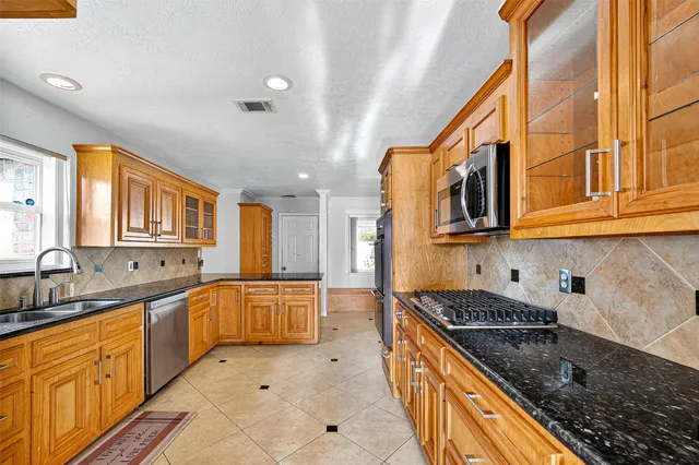 a large kitchen with stainless steel appliances granite countertop a sink and cabinets