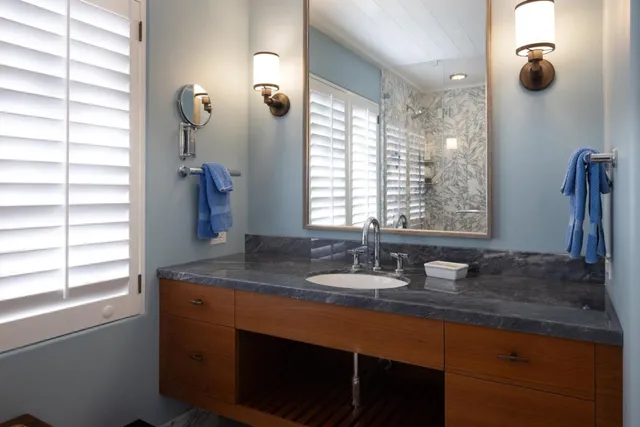 a bathroom with a granite countertop sink and a mirror