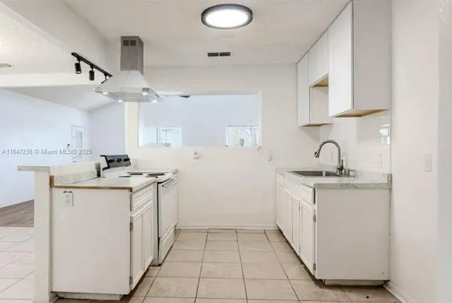a kitchen with granite countertop a sink a stove and cabinets