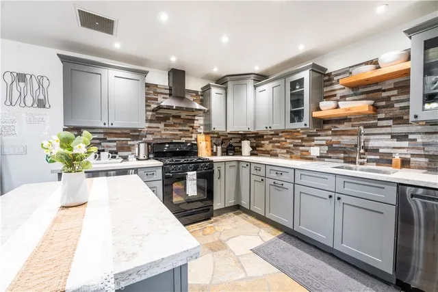 a kitchen with stainless steel appliances kitchen island granite countertop a table chairs and a refrigerator