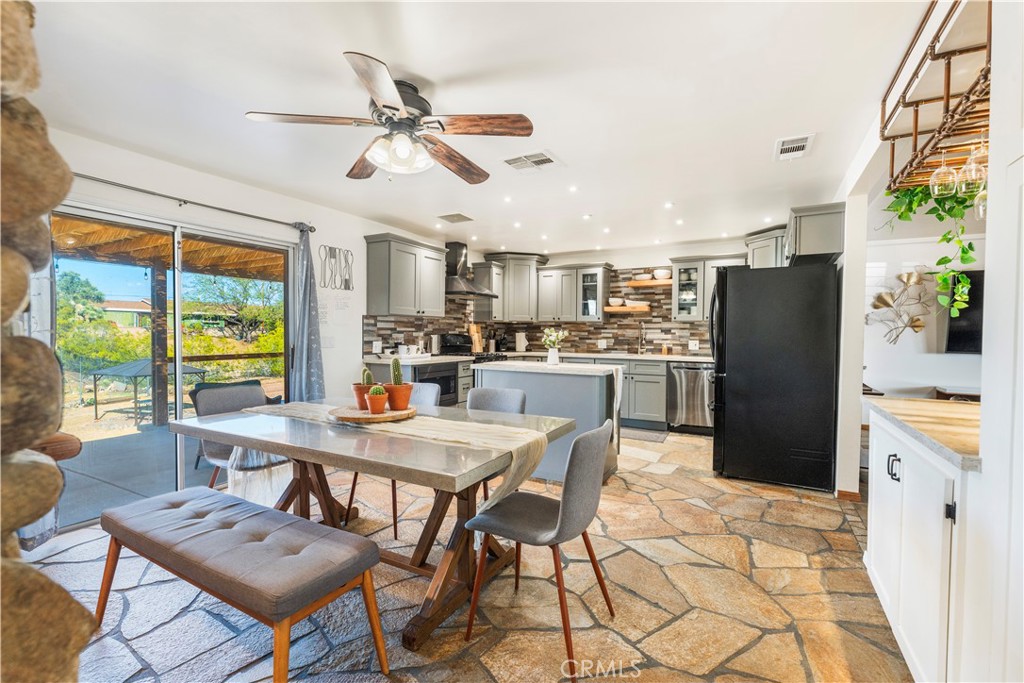 7071 Rubidoux Avenue Yucca Valley, CA 92284 - Photo 36 of 50 a kitchen with stainless steel appliances kitchen island granite countertop a table chairs and a refrigerator