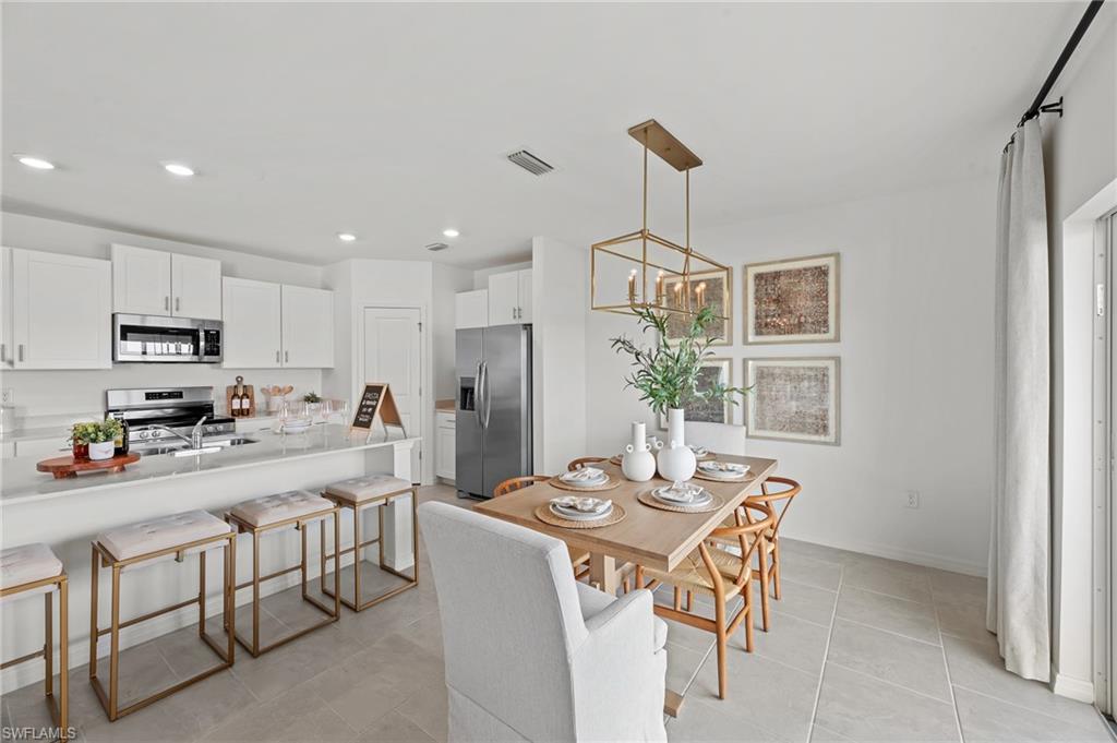 17251 Monte Isola Way North Fort Myers, FL 33917 - Photo 16 of 39 a kitchen with a dining table chairs stainless steel appliances and cabinets