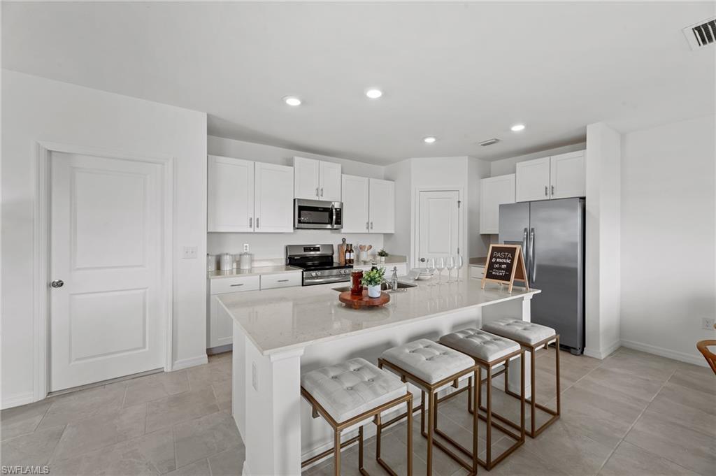17251 Monte Isola Way North Fort Myers, FL 33917 - Photo 10 of 39 a kitchen with a refrigerator a stove top oven a sink and chairs