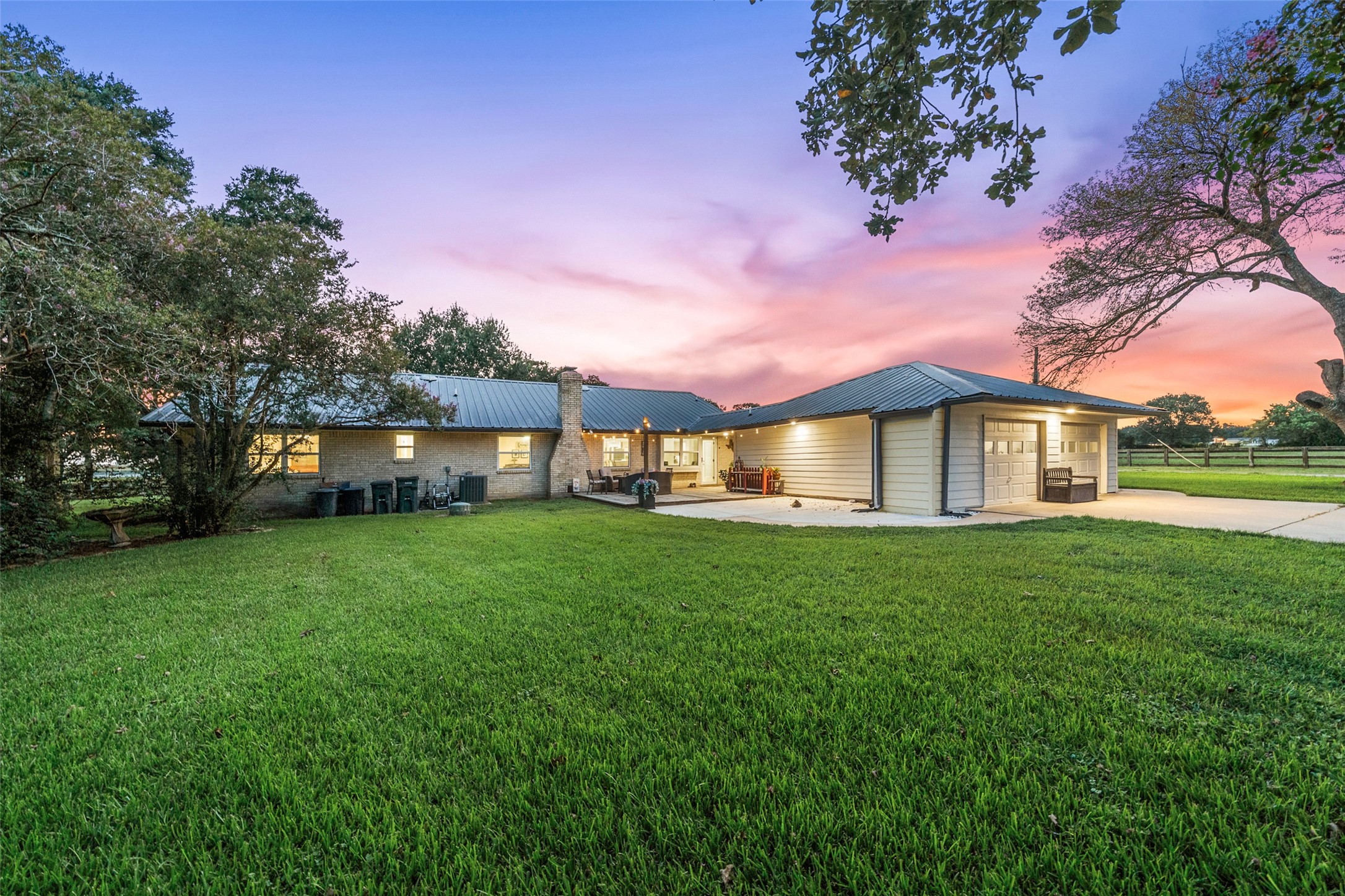 21348 Farm To Market 359 Hempstead, TX 77445 - Photo 31 of 48 Rear view of the home and garage highlights the metal roof, upgraded Hardiplank siding, and extended concrete work for added parking and function.