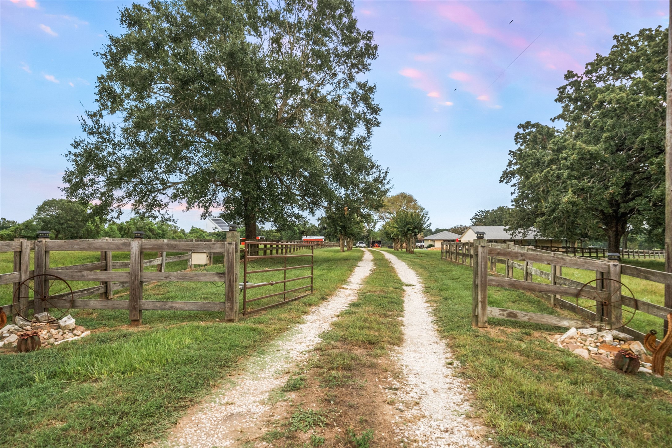 21348 Farm To Market 359 Hempstead, TX 77445 - Photo 6 of 48 Long gravel drive with gated entry creates a private approach to the property, framed by mature trees and cross-fenced pastures.