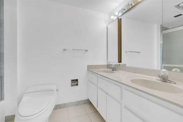 a bathroom with a granite countertop toilet sink and mirror