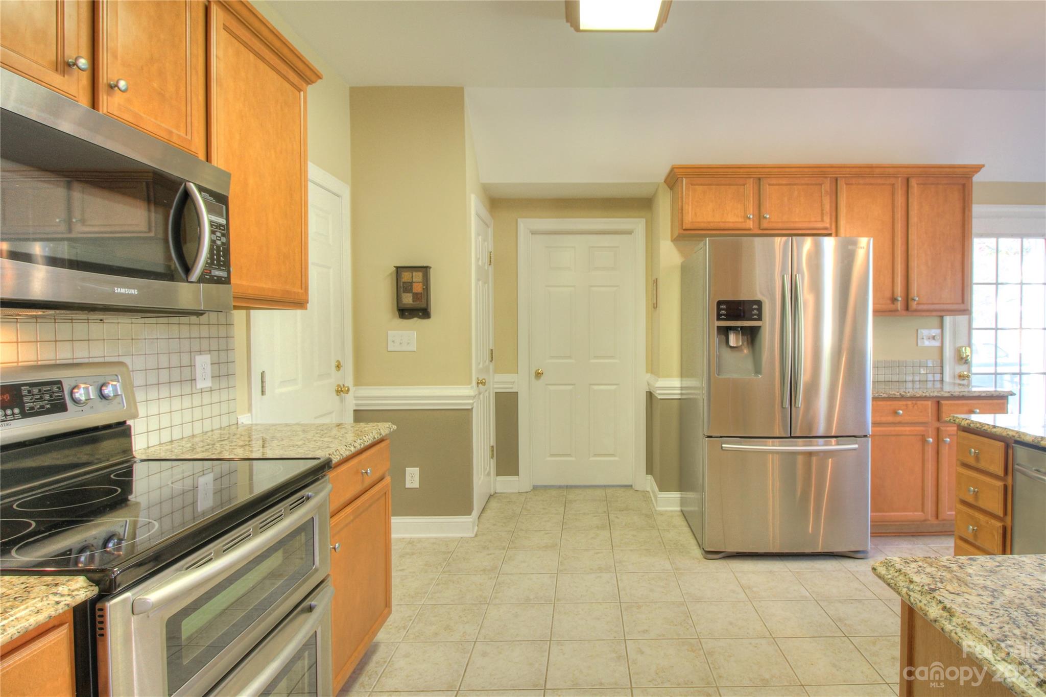 1016 Wesley Downs Road Wesley Chapel, NC 28110 - Photo 10 of 40 a kitchen with stainless steel appliances granite countertop a refrigerator and a sink