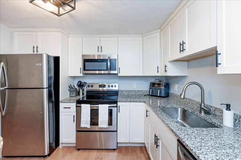 7 Walker Road, Unit 9 North Andover, MA 01845 - Photo 8 of 23 a kitchen with stainless steel appliances granite countertop a refrigerator sink and stove