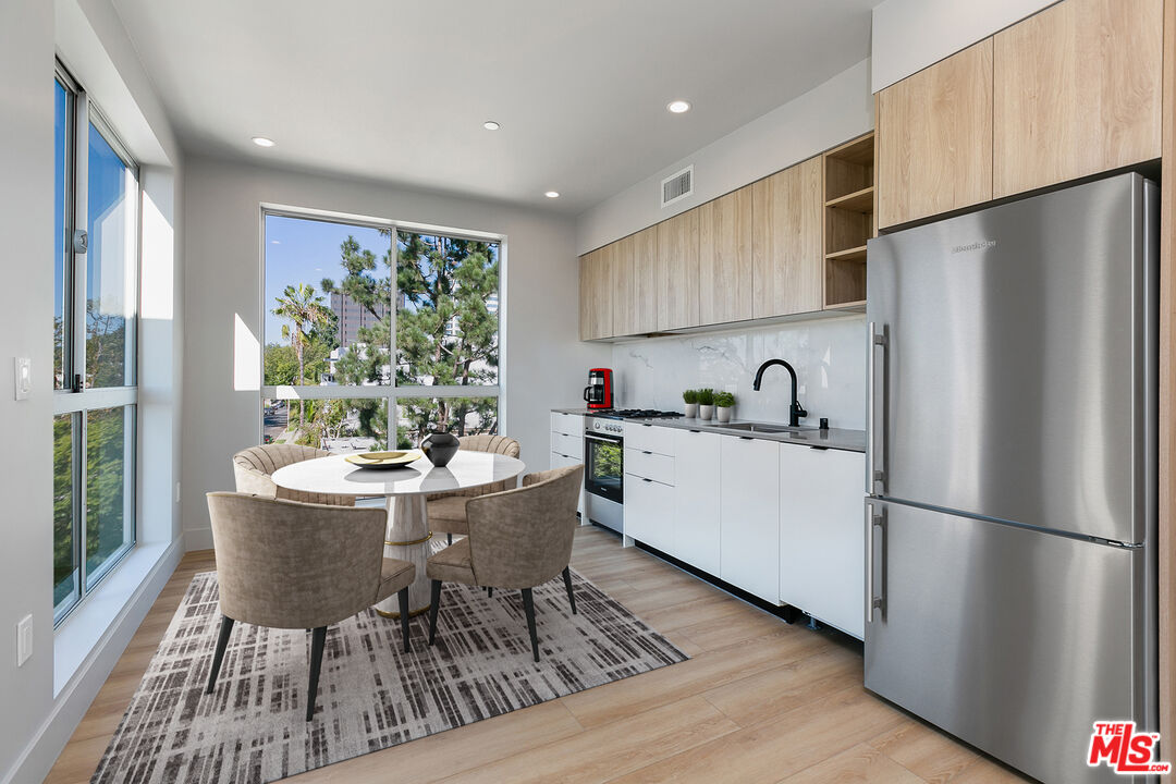 12431 Rochester Avenue, Unit 206 Los Angeles, CA 90025 - Photo 3 of 23 a kitchen with stainless steel appliances a dining table chairs refrigerator and sink