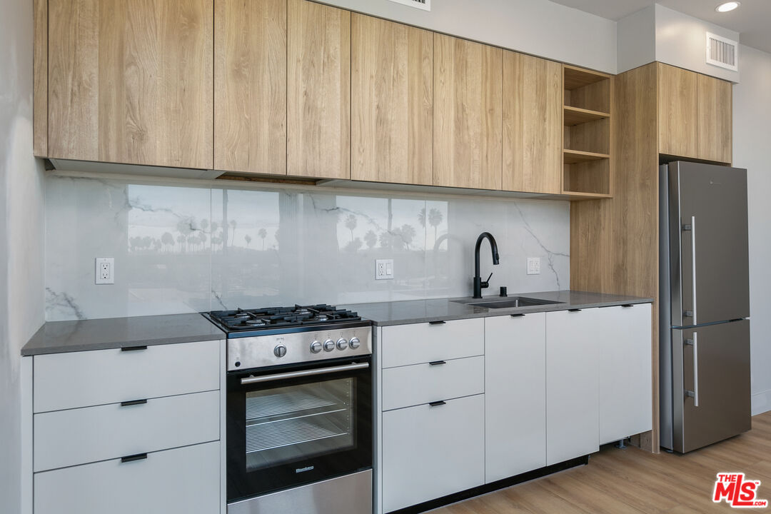 12431 Rochester Avenue, Unit 206 Los Angeles, CA 90025 - Photo 4 of 23 a kitchen with stainless steel appliances granite countertop white cabinets and a stove top oven