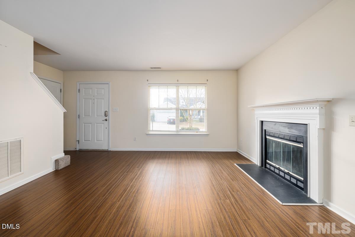 3617 Hamilton Mill Drive Raleigh, NC 27616 - Photo 4 of 20 an empty room with wooden floor fireplace and windows