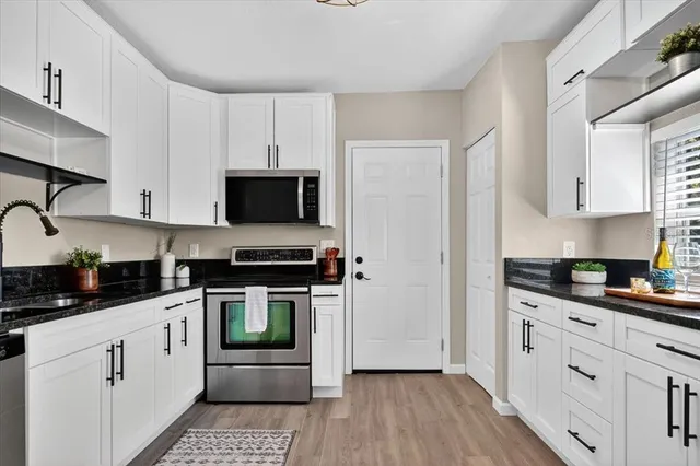 a kitchen with stainless steel appliances white cabinets a stove a sink and a microwave