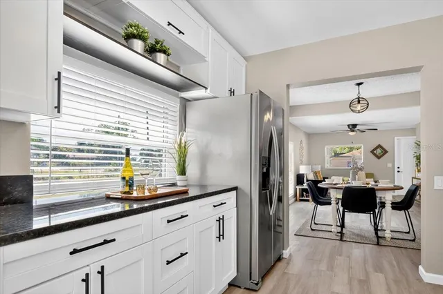 a kitchen with stainless steel appliances granite countertop a refrigerator a sink a stove and white cabinets