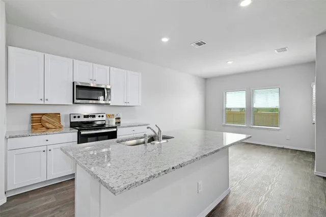a kitchen with granite countertop a sink a counter top space appliances and cabinets