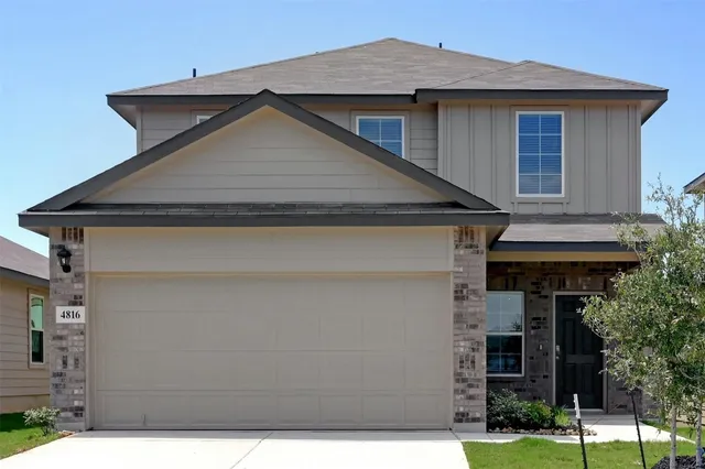 a view of a house with wooden fence and a yard