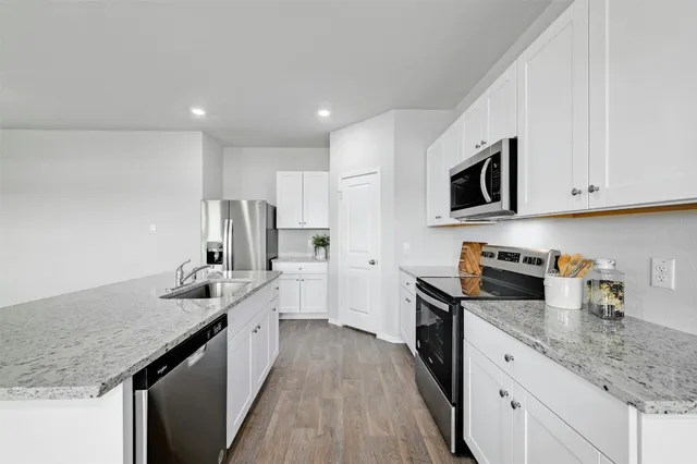 a kitchen with granite countertop sink stainless steel appliances and white cabinets