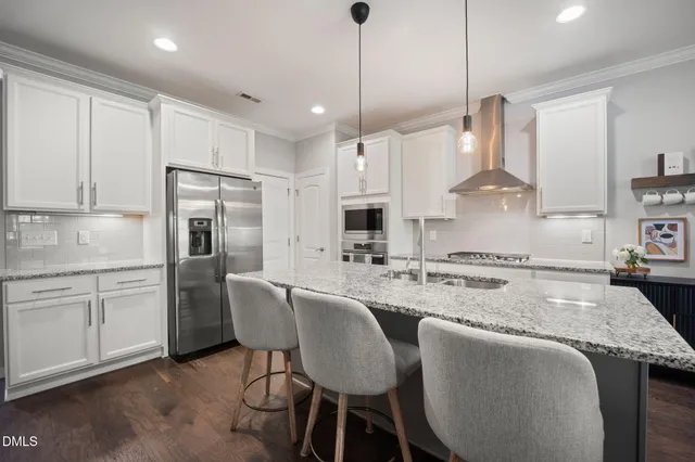 a kitchen with stainless steel appliances granite countertop a stove a sink a refrigerator a dining table and chairs with wooden floor