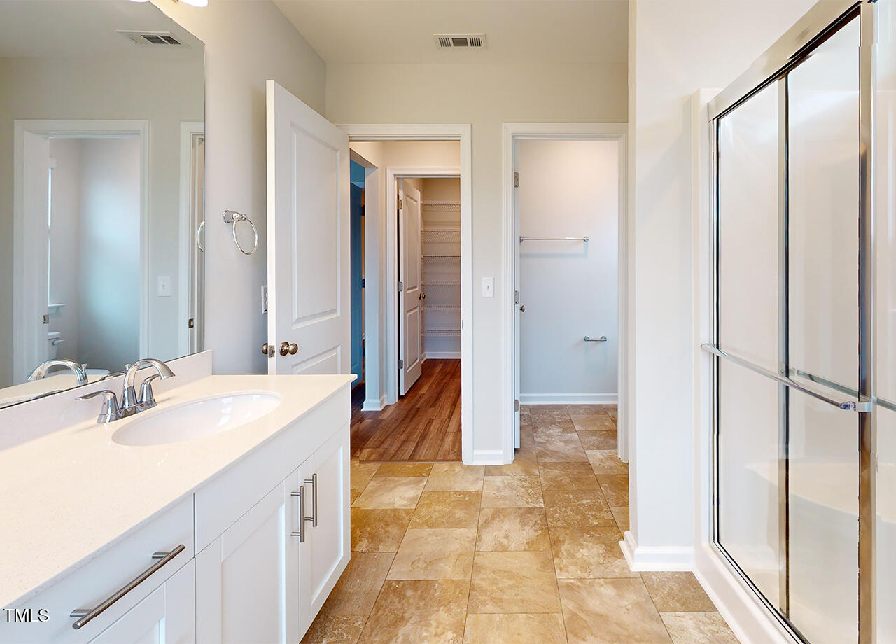 314 Lemon Leaf Place, Unit MANDEVILLA Holly Springs, NC 27540 - Photo 17 of 23 a spacious bathroom with a mirror a double vanity sink and a shower