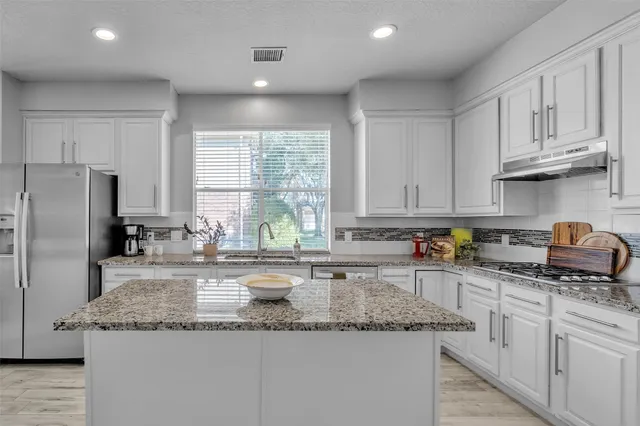 a kitchen with stainless steel appliances granite countertop a sink a stove and cabinets