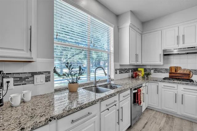 a kitchen with stainless steel appliances granite countertop a sink a stove and cabinets