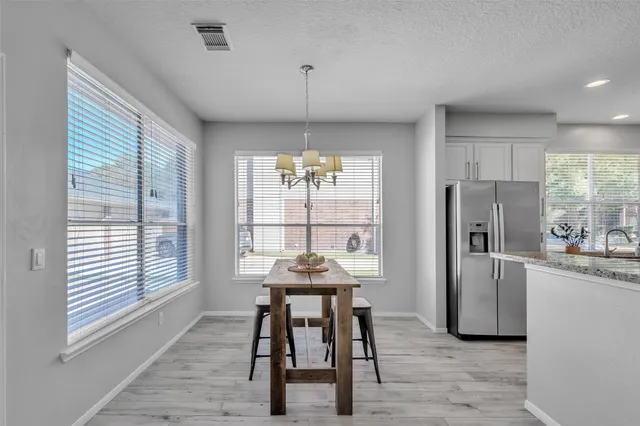 a kitchen with stainless steel appliances granite countertop a refrigerator a sink a stove a dining table and chairs