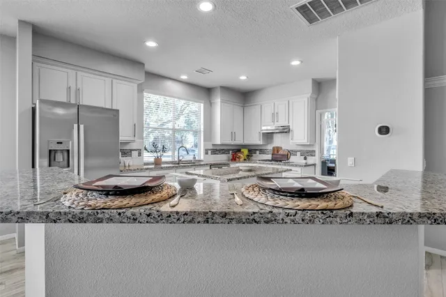 a kitchen with kitchen island granite countertop a sink and a stove