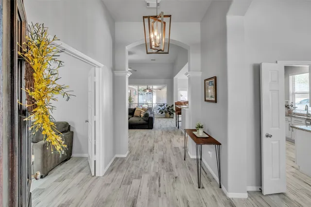 a view of a hallway with wooden floor and a livingroom with furniture