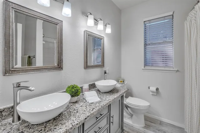 a bathroom with a granite countertop toilet sink and mirror