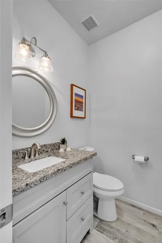 a bathroom with a granite countertop toilet sink and mirror