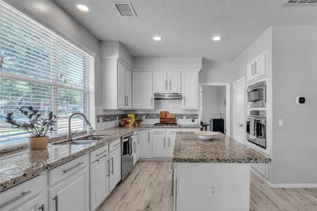 a kitchen with stainless steel appliances granite countertop a sink a stove and cabinets