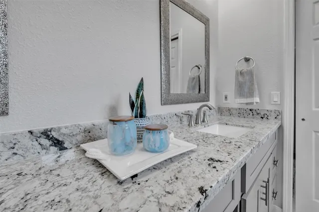 a bathroom with a granite countertop sink and a mirror