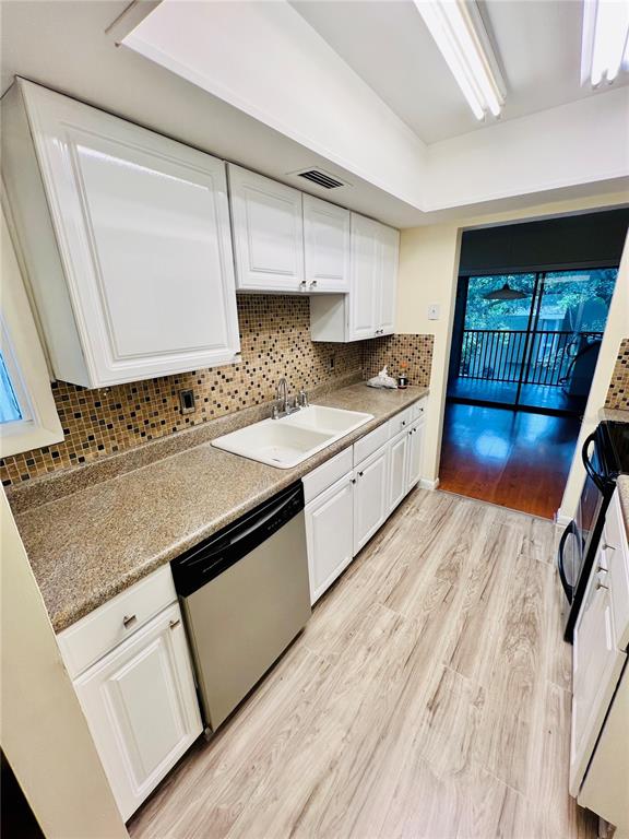 6057 Windhover Drive, Unit E08 Orlando, FL 32819 - Photo 14 of 19 a kitchen with stainless steel appliances granite countertop a sink stove and white cabinets with wooden floor
