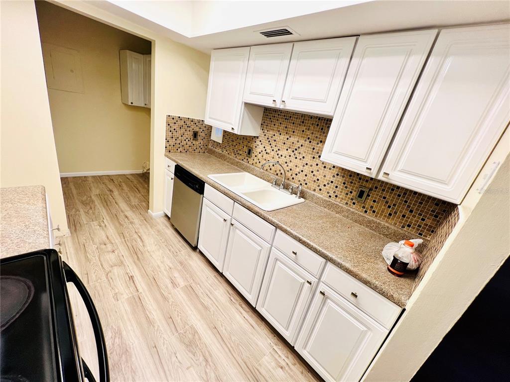 6057 Windhover Drive, Unit E08 Orlando, FL 32819 - Photo 5 of 19 a kitchen with granite countertop white cabinets and white appliances