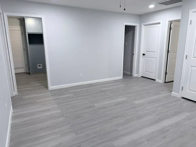 an empty room with wooden floor and closet area