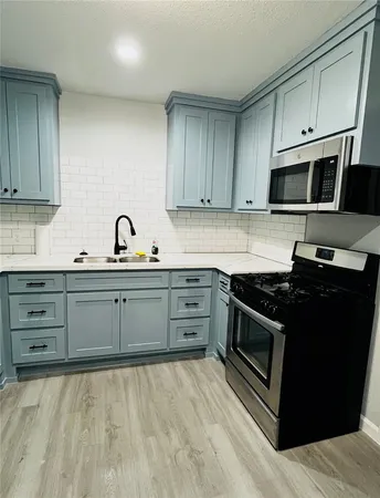 a kitchen with stainless steel appliances granite countertop a stove a sink and a microwave