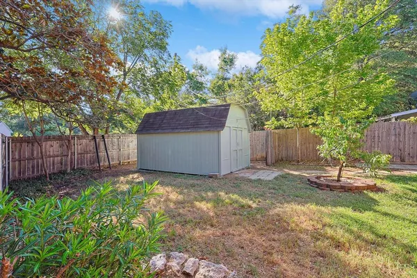 a backyard of a house with plants and trees with wooden fence