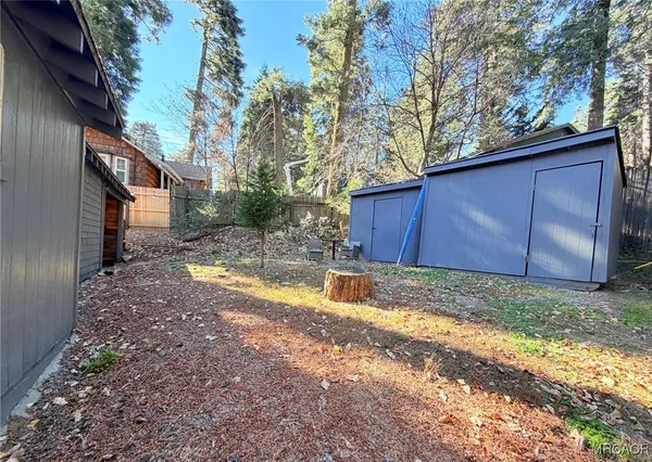 a view of a backyard with large trees and wooden fence