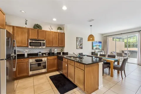 a kitchen with granite countertop stainless steel appliances a stove a sink a dining table and chairs