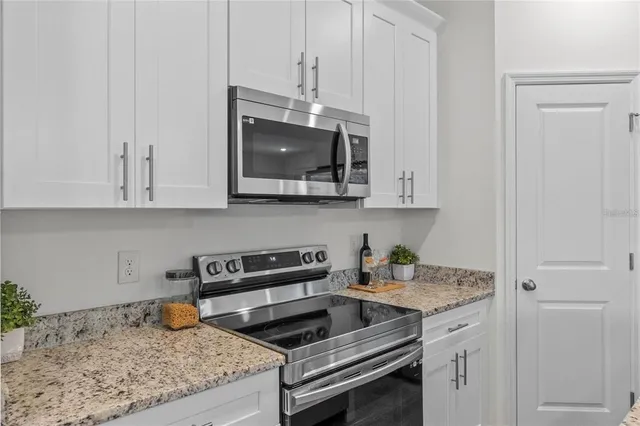 a kitchen with granite countertop a stove and a white cabinets